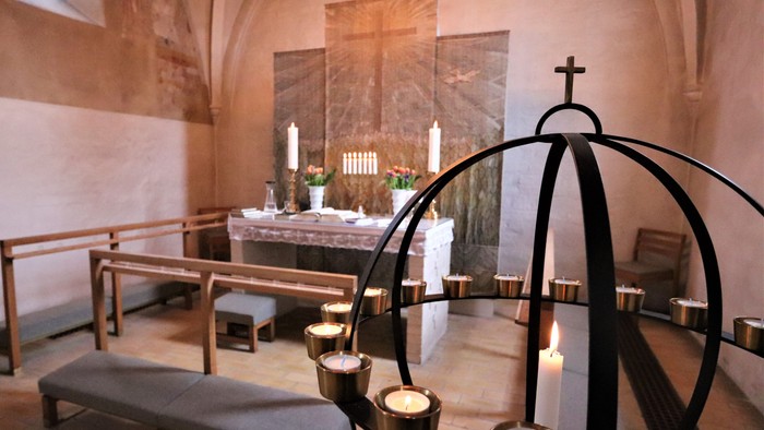 En lille kapel med alter, bænke og lysestage.