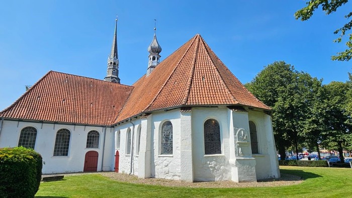 Weißes Kirchegebäude mit rotem Dach und Turm im Grünen