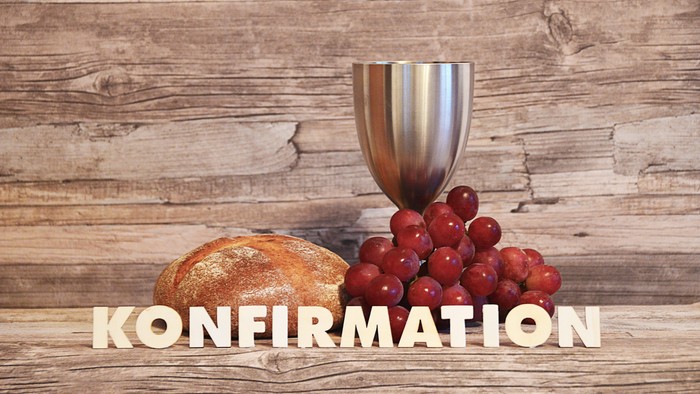 Holzplatte mit Kelch, Brot und Trauben, darunter das Wort "Konfirmation"