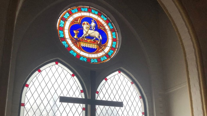 Buntes Kirchenfenster mit Kreuz darunter