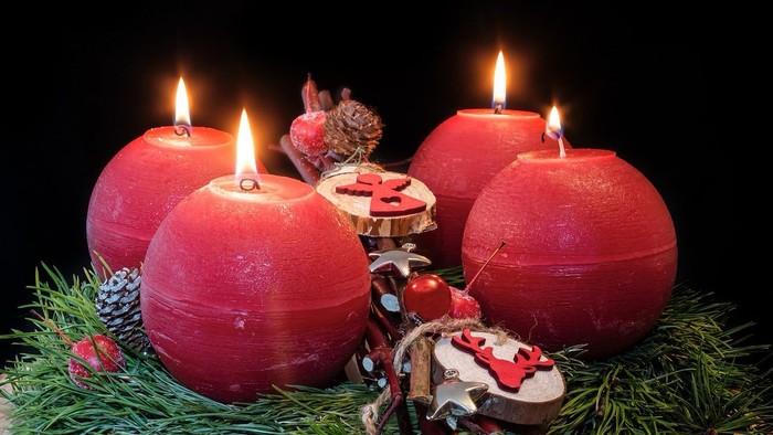 Vier brennende rote Kerzen in Weihnachtsdekoration