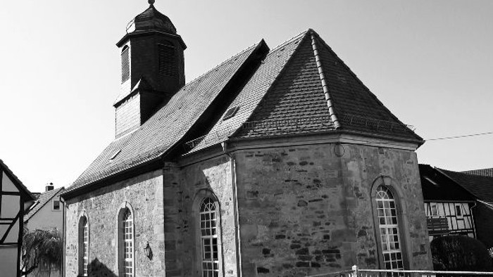Schwarz-Weiß-Foto einer alten Steinkirche mit einem Kirchturm.