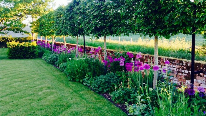 Lush garden with manicured lawn, colorful flowers, and neatly trimmed hedges