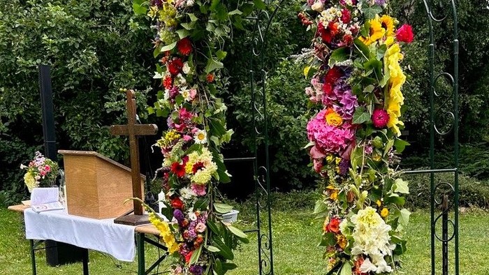 Blumenbogen auf Wiese mit Tisch und Stühlen im Garten