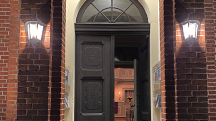 Ein schwarzes Tür in einem Ziegelbogen mit zwei Wandleuchten