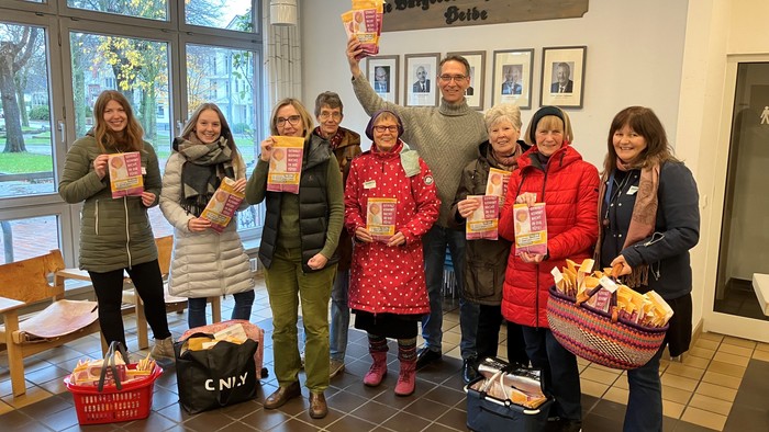 Eine Gruppe von Menschen hält Bücher und Taschen in einem Raum mit einem Schild "Büchertauschtag".