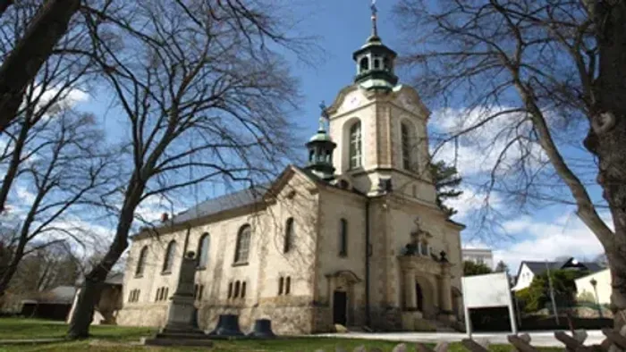 Alte Kirche mit hohem Turm und nackten Bäumen im Vordergrund