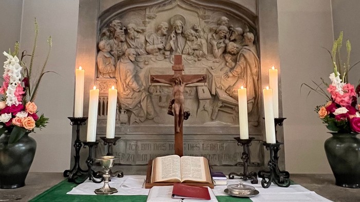 Altar mit Kreuz, Kerzen und Blumen in Kirche