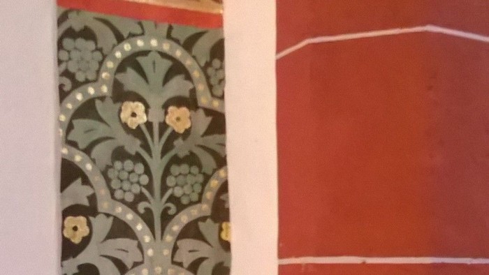 Das Bild zeigt eine verzierte, vertikale Wanddekoration mit Pflanzenmustern.