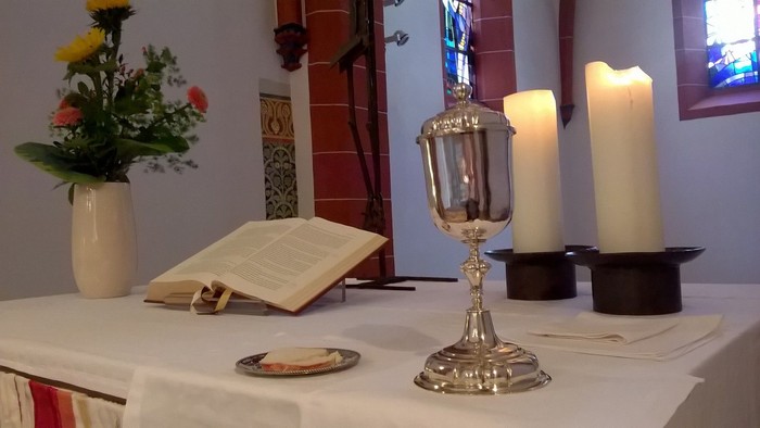 Ein Altar mit Kelch, Kerzen und Blumen in einer Kirche