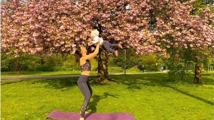 Frau übt Yoga im Park unter blühendem Baum