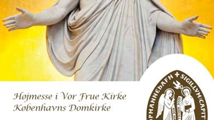 Statue af Jesus med åbne arme, omgivet af religiøs symbolik og tekster på dansk