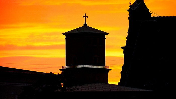 Kirketårne i silhuet badet i levende solnedgangsfarver.