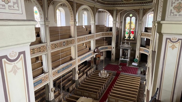 Große Bibliothek mit hohen Bücherregalen und Stufen, die zu einem Podium führen