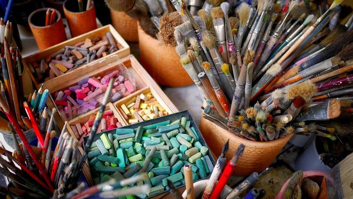 Viele Buntstifte und Pinsel in verschiedenen Behältern