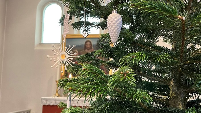 En juletree med pynt og et billede af en kvinde i baggrunden