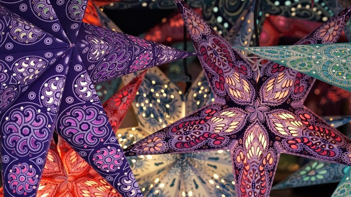 Bunte papirstjerner med udskærede mønstre og lys.