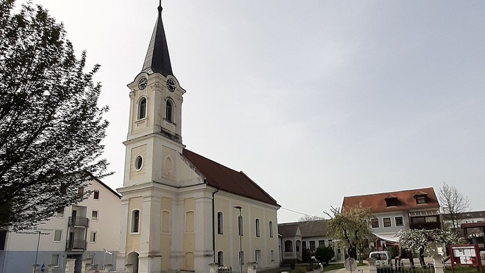 Kirchengebäude mit hohem Turm und Uhr in kleiner Stadt