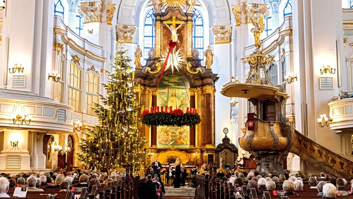 Indre del af en prægtig kirke med højt alter og juletræ.