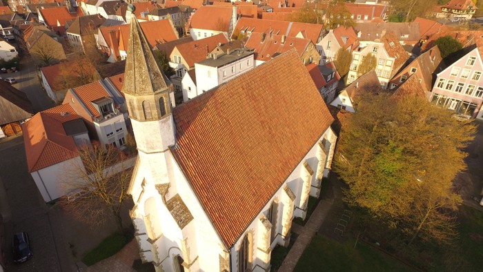 Die Luftaufnahme zeigt eine weiße Kirche mit hohem Turm in einem Dorf.