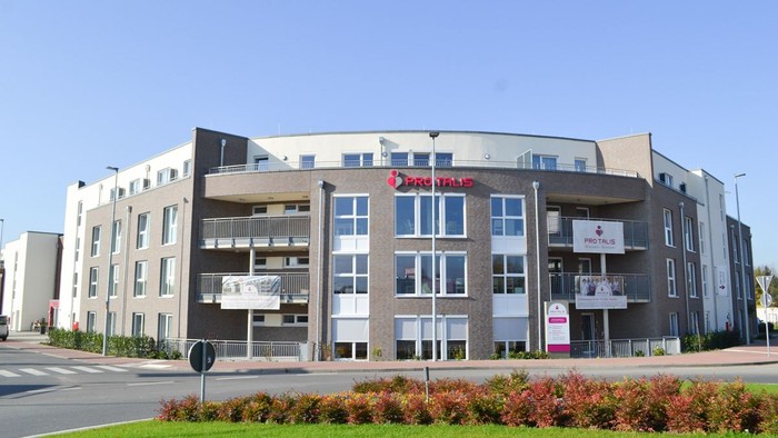 Modernes Gebäude mit großen Fenstern und Parkplatz im Vordergrund