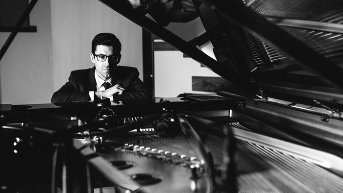 Man in suit playing piano.