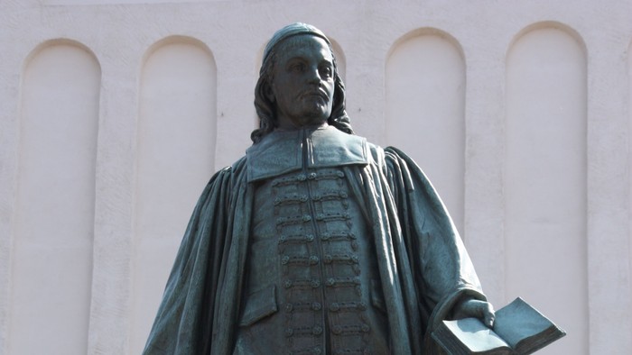Die Bronzestatue eines Mannes mit Buch und Federkiel.