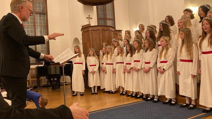 En mand dirigerer en kirkekor, mens de synger i en stor kirke.