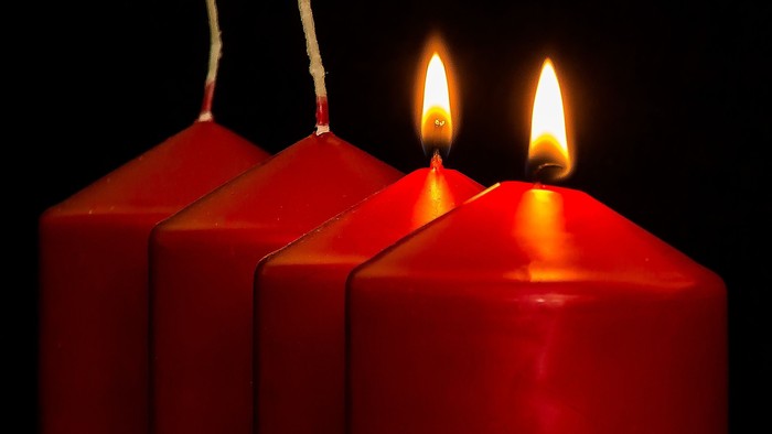 Vier rote Kerzen, drei unangezündet, eine angezündet