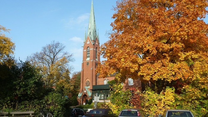 Bunte Herbstbäume vor Kirche und Autos