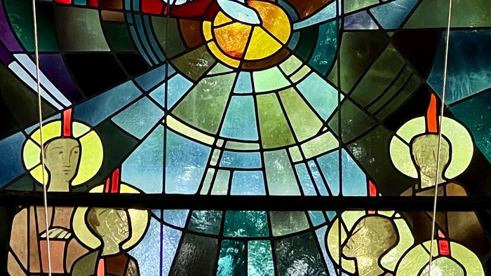 Buntglasfenster mit abstrakten religiösen Symbolen und kreisförmigen Heiligenfiguren mit Heiligenscheinen.