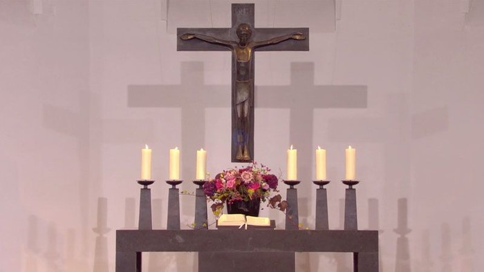 Ein Altar mit Kreuz, Kerzen und Blumen in einer Kirche