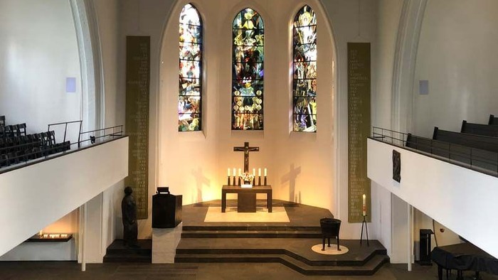 Die Kirche hat hohe Decken, bunte Fenster und eine zentrale Kanzel mit Kerzen.