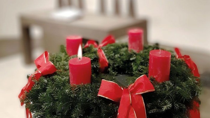 Ein Adventskranz mit vier roten Kerzen und roten Schleifen auf einem Tisch