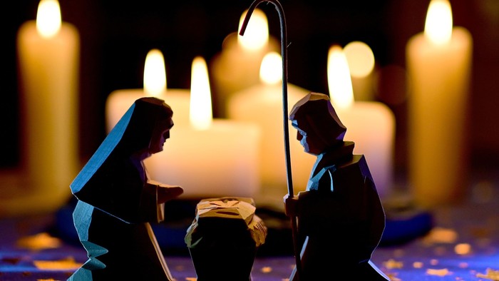 En julekrybbe med Maria, Josef og barnets kuld, omgivet af lysende lygter.