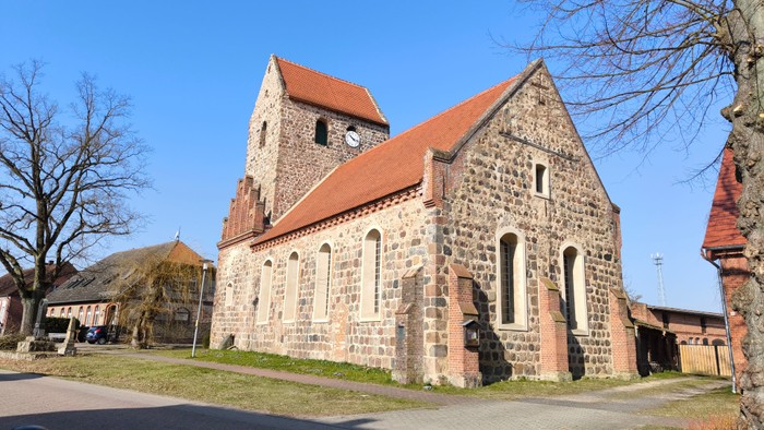 Altes steinernes Kirchengebäude mit rotem Dach und leuchtend blauem Himmel