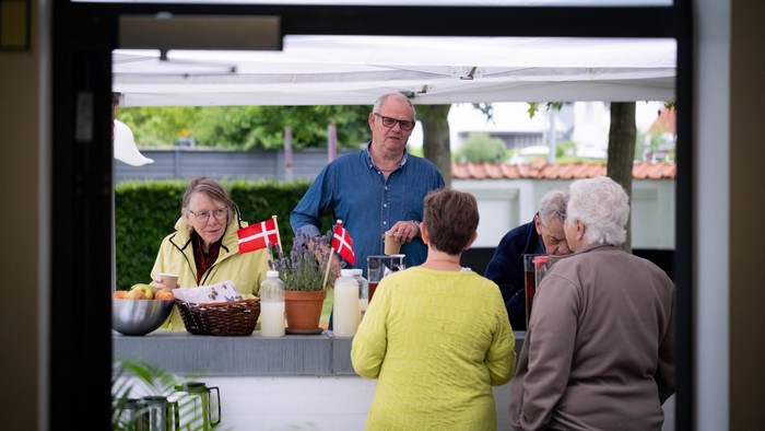 En gruppe mennesker samles ude, der er servet med mad og drikkevarer