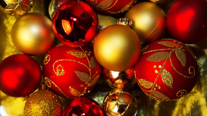En samling juledekorationer i røde og gyldne farver med guldtrådsdetaljer.