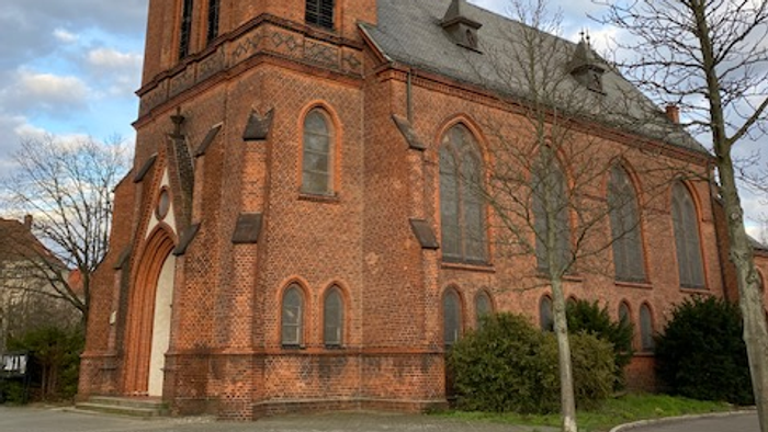 Große rote Ziegelkirche mit hohem Turm und spitzen Fenstern.