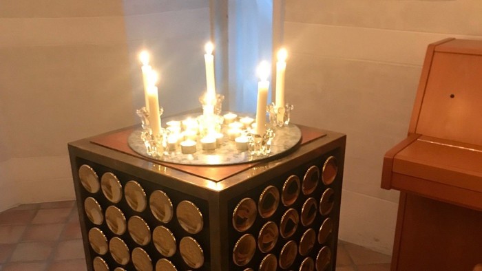 En lille alter med lysende lys og en orgel i baggrunden