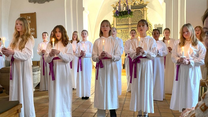 Pigekor med lys i hænderne ved gudstjeneste 