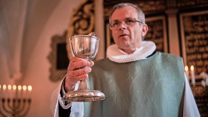 Mand i religiøs tjeneste med kalk i kirke