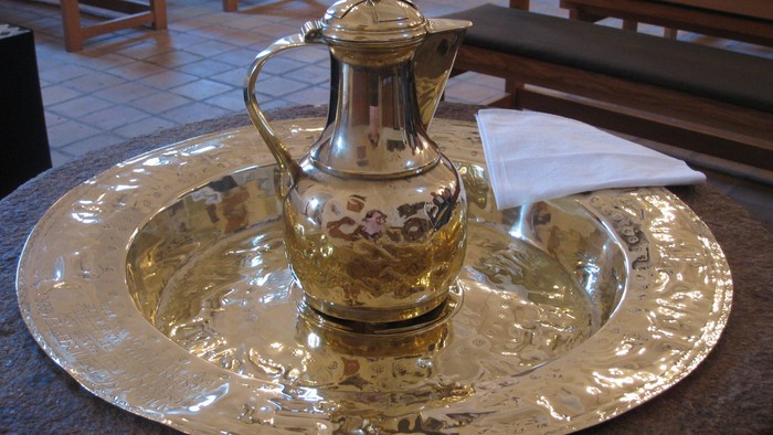 En sølv tekanne på en sølv trays med et håndklæde