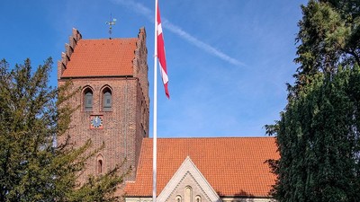 Kirke med tårn og rødt tag med flag i vinden
