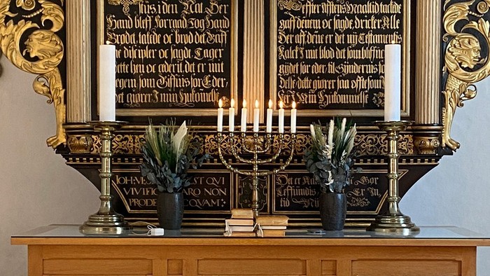 En prægtig altertavle med gyldne detaljer og lysende kandlelygter.