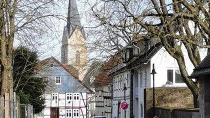 Eine malerische Straße mit einem parkenden Auto, gesäumt von alten Gebäuden und einer Kirche im Hintergrund.