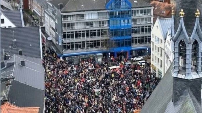 Große Menschenmenge vor blauem Gebäude in Stadtzentrum.