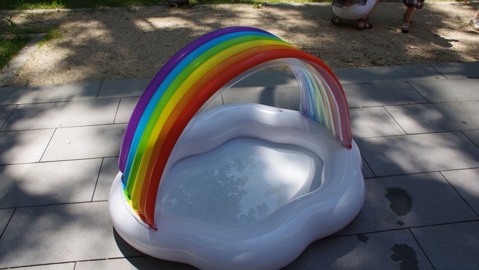 Ein bunter Regenbogen-Baldachin über einem kleinen Pool im Freien