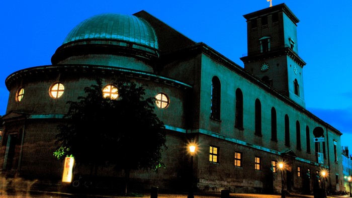 En stor kirke med en kuppel og tårn, belyset blåt og med lys i vinduerne.