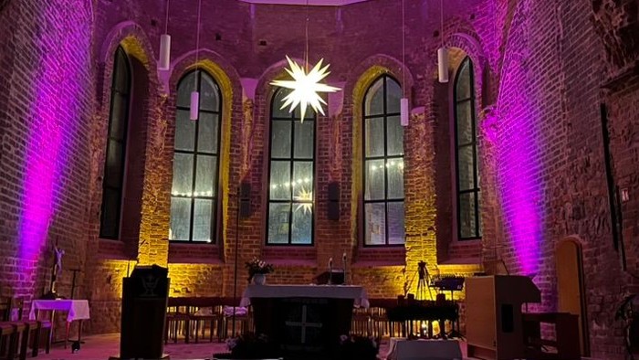 Gekonnte Beleuchtung in historischem Kirchenraum mit hohen Fenstern und Holzbänken